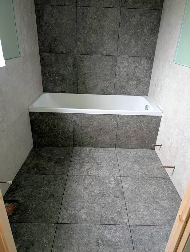 Bathroom in stone effect tiles with a tiled bath panel